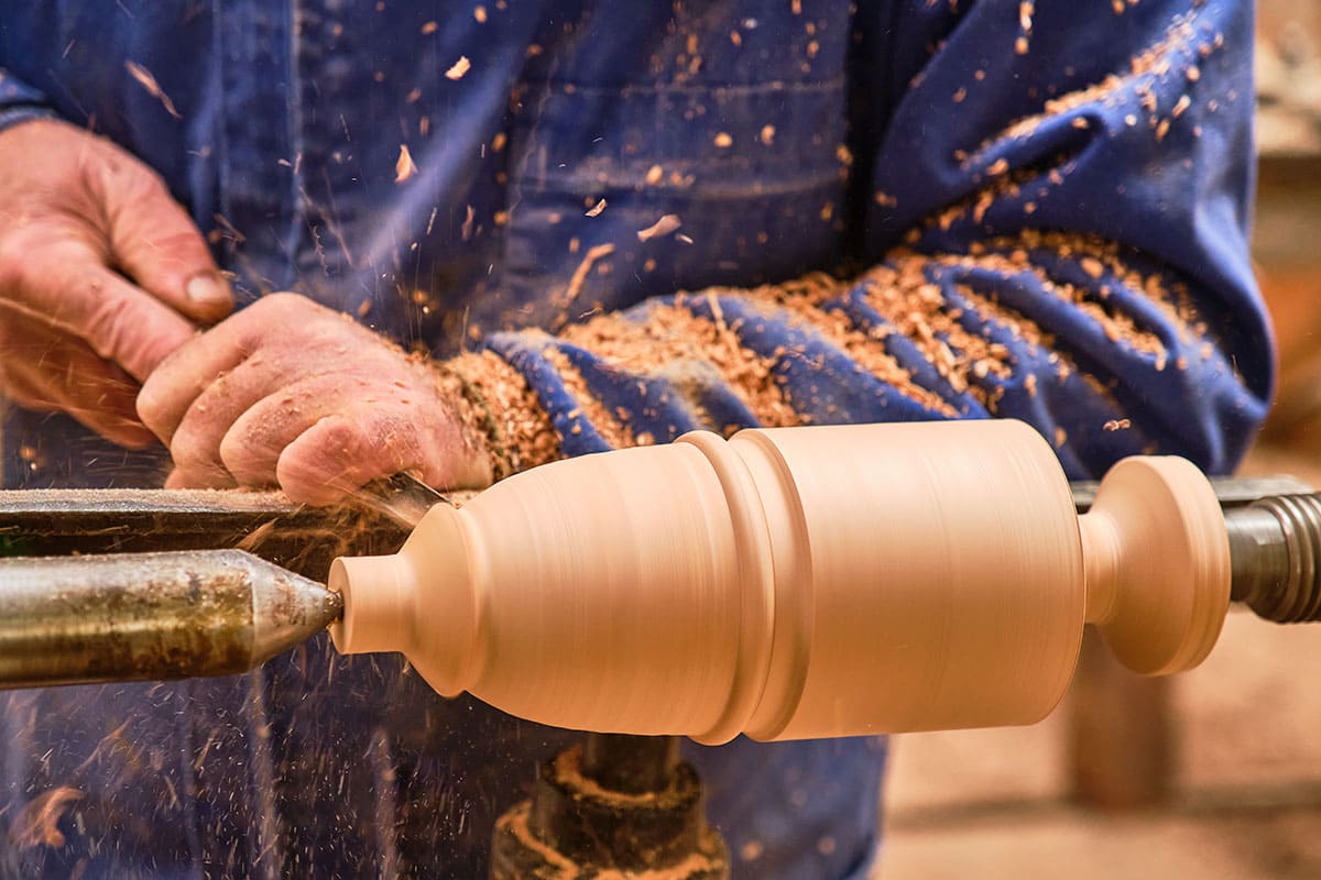 A woodturner shaping a spindle on a lathe
